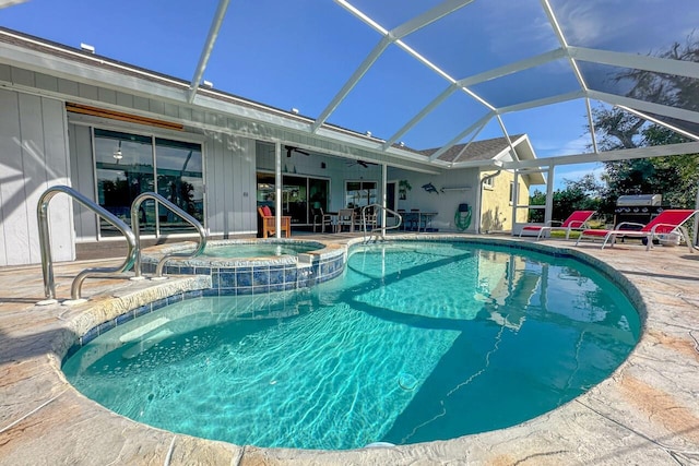 view of swimming pool featuring a patio area, ceiling fan, glass enclosure, and an in ground hot tub