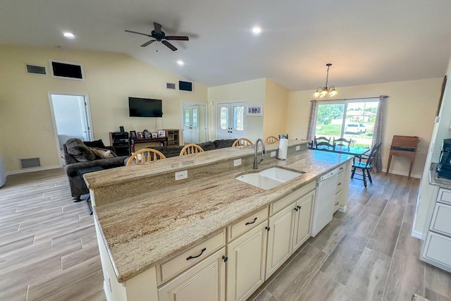 kitchen featuring light stone countertops, light wood-type flooring, sink, dishwasher, and hanging light fixtures