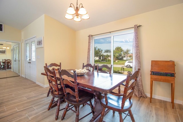 dining area featuring a chandelier, lofted ceiling, and light hardwood / wood-style flooring