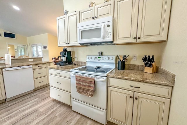 kitchen featuring light stone countertops, light wood-type flooring, white appliances, and cream cabinets