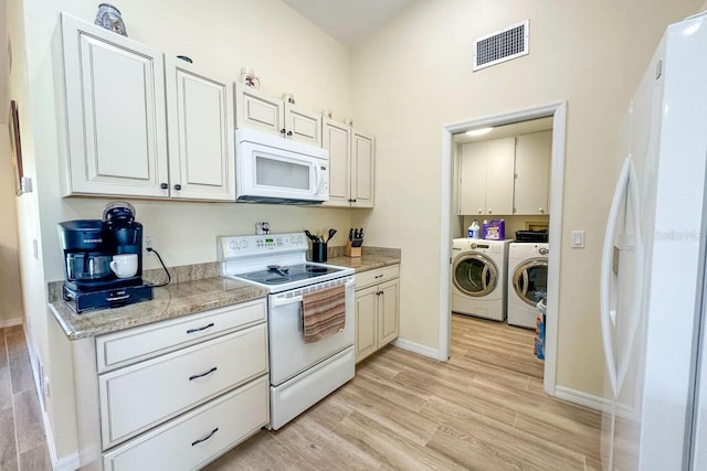 kitchen featuring washer and dryer, white cabinetry, white appliances, and light hardwood / wood-style flooring