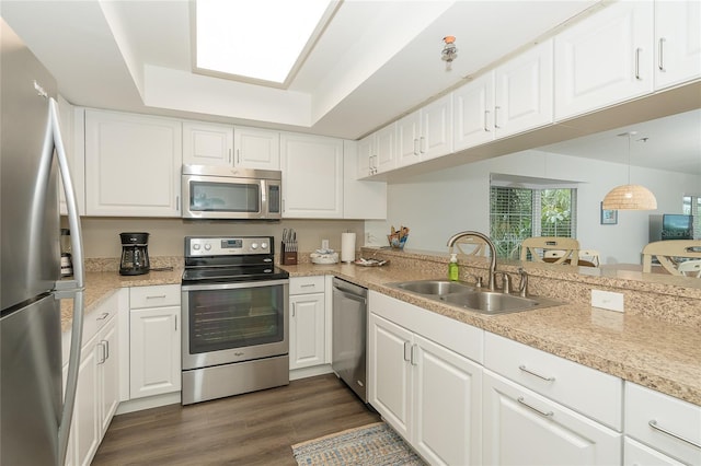 kitchen featuring appliances with stainless steel finishes, dark wood-type flooring, sink, decorative light fixtures, and white cabinetry