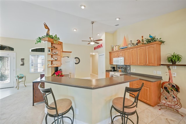 kitchen with a kitchen breakfast bar, lofted ceiling, ceiling fan, and white appliances