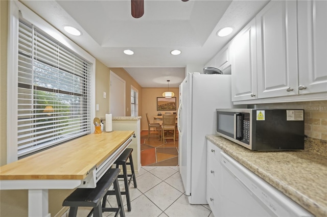 kitchen featuring dishwasher, backsplash, light tile patterned floors, decorative light fixtures, and white cabinetry