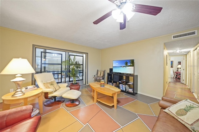 living room with ceiling fan, tile patterned flooring, and a textured ceiling