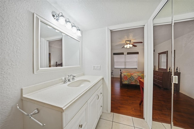 bathroom with vanity, ceiling fan, wood-type flooring, and a textured ceiling