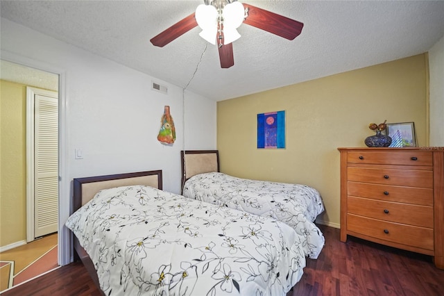 bedroom featuring a textured ceiling, dark hardwood / wood-style floors, and ceiling fan