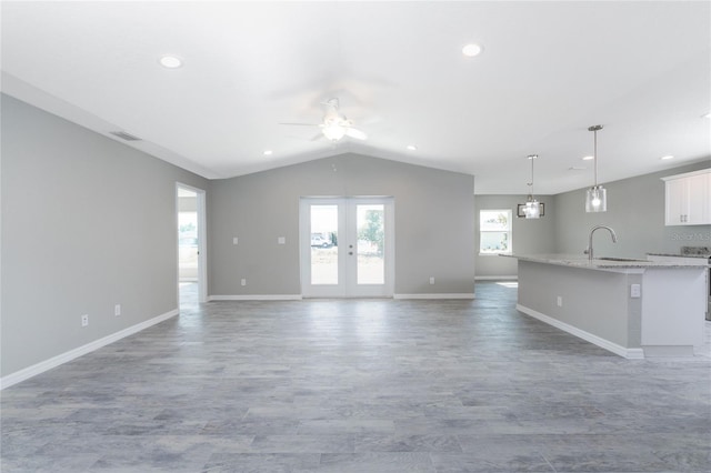 unfurnished living room featuring ceiling fan, lofted ceiling, sink, and french doors