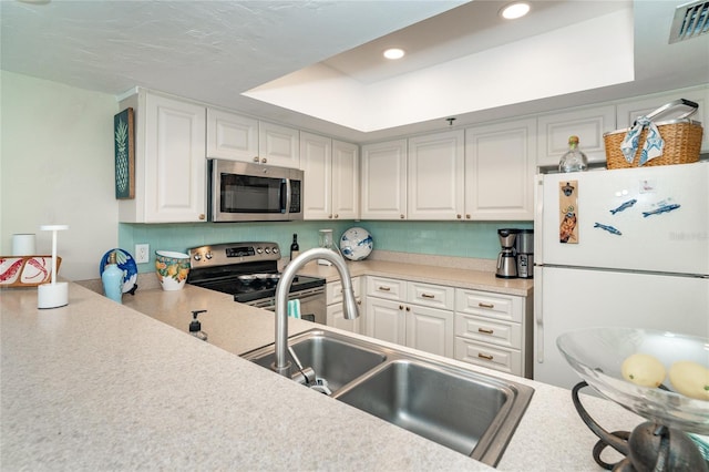 kitchen featuring a raised ceiling, sink, tasteful backsplash, white cabinetry, and stainless steel appliances