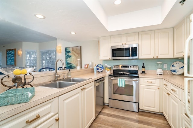 kitchen featuring kitchen peninsula, light wood-type flooring, stainless steel appliances, and sink