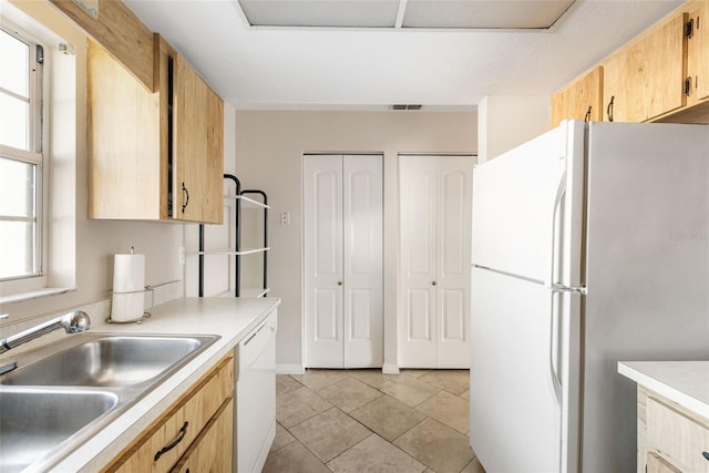 kitchen featuring light tile patterned floors, white appliances, light brown cabinetry, and sink