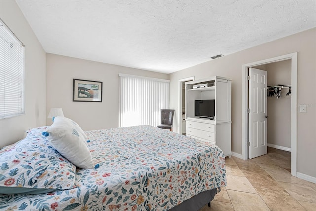 tiled bedroom with multiple windows, a spacious closet, and a closet