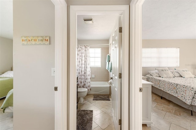 interior space featuring toilet, tile patterned floors, and shower / bathtub combination with curtain