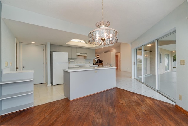 kitchen featuring electric range, white refrigerator, a notable chandelier, decorative light fixtures, and light wood-type flooring