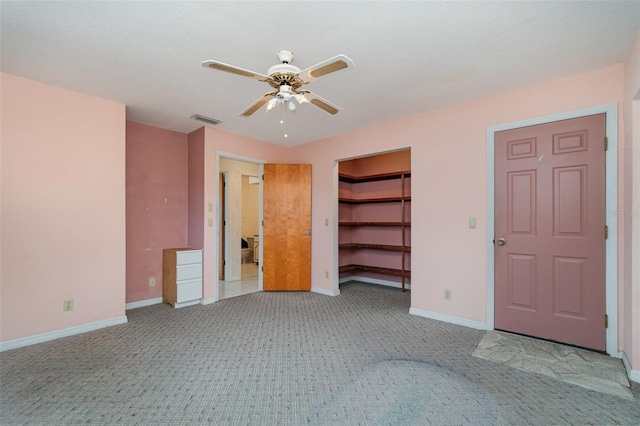 unfurnished bedroom featuring ceiling fan, light colored carpet, a closet, and a walk in closet