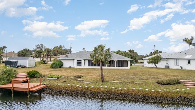 rear view of house featuring a water view, a yard, and a sunroom