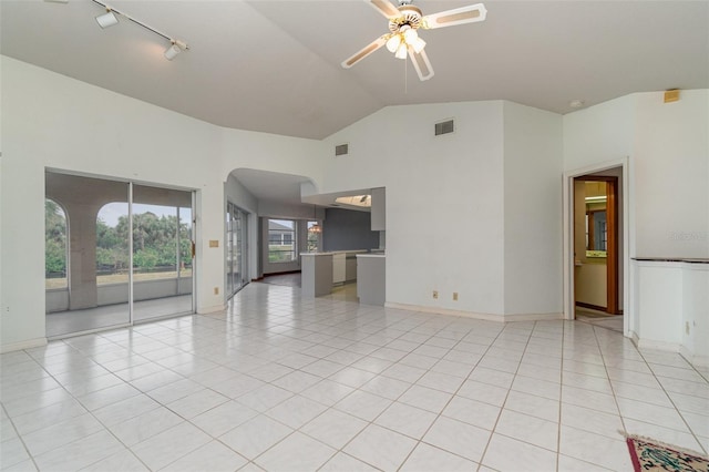 unfurnished living room featuring rail lighting, lofted ceiling, light tile patterned floors, and ceiling fan