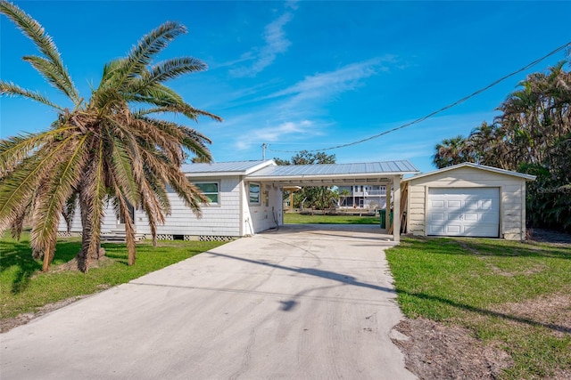 single story home with a carport, a garage, an outbuilding, and a front yard