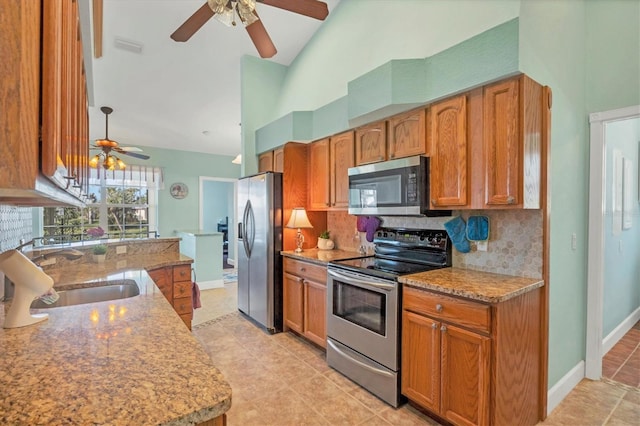 kitchen with light stone countertops, tasteful backsplash, stainless steel appliances, ceiling fan, and sink