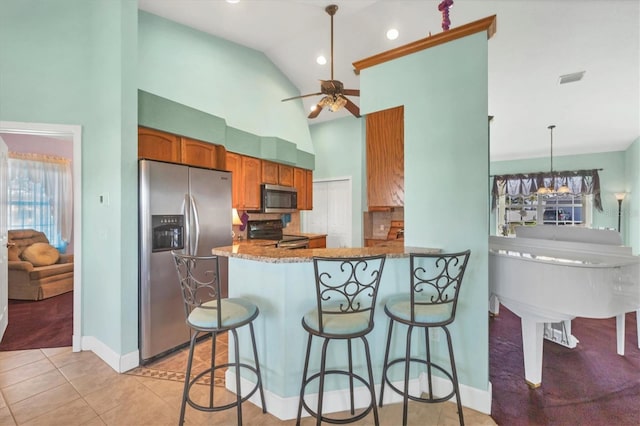 kitchen featuring stainless steel appliances, kitchen peninsula, pendant lighting, light tile patterned floors, and ceiling fan with notable chandelier