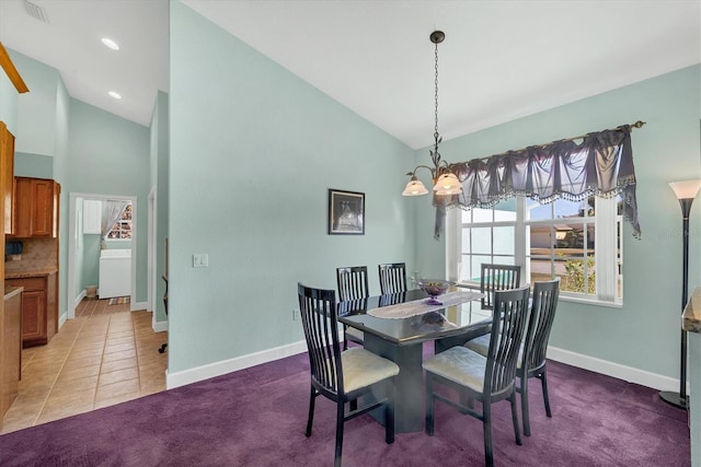 carpeted dining area featuring high vaulted ceiling and an inviting chandelier