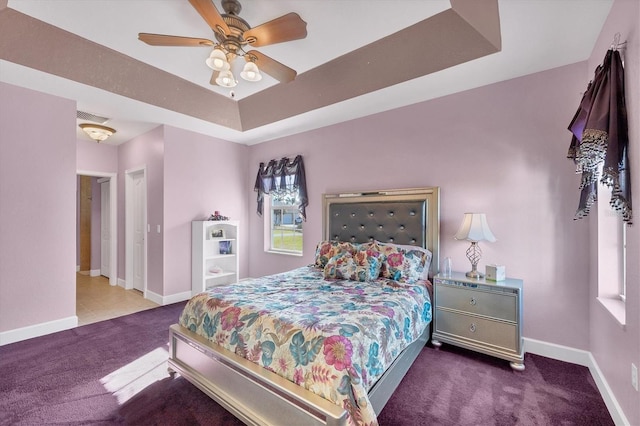 bedroom featuring carpet flooring, a tray ceiling, and ceiling fan