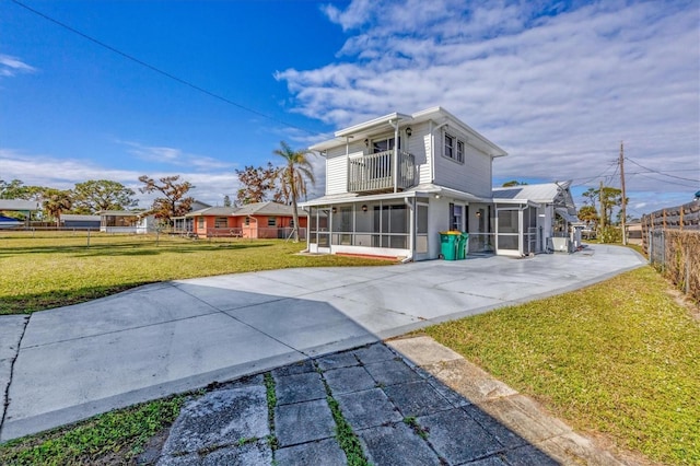 back of house with a balcony, a yard, and a sunroom