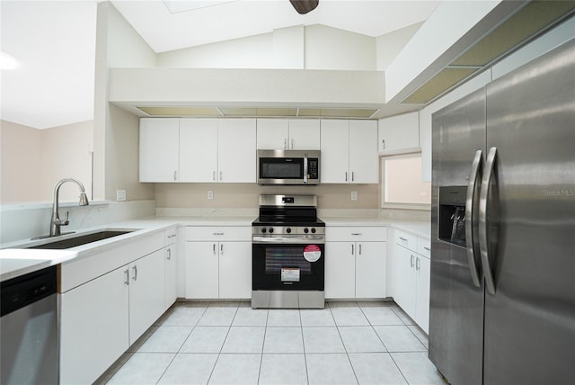 kitchen featuring appliances with stainless steel finishes, vaulted ceiling, white cabinetry, and sink