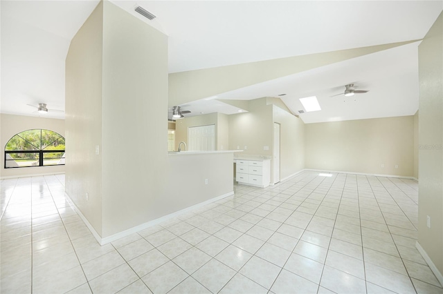 empty room featuring ceiling fan, light tile patterned flooring, and lofted ceiling with skylight