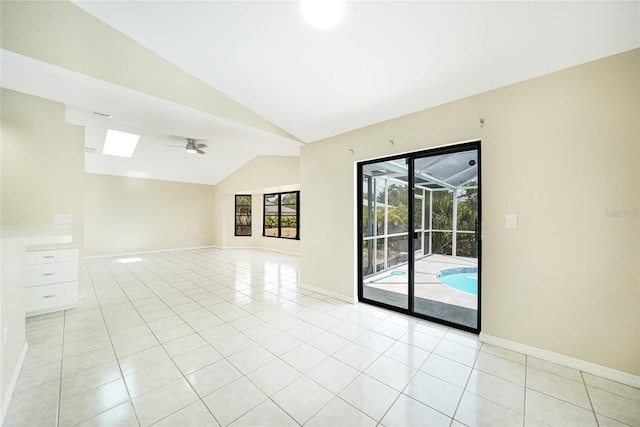 unfurnished room featuring lofted ceiling with skylight, ceiling fan, and light tile patterned flooring