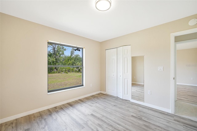 unfurnished bedroom with light wood-type flooring and a closet