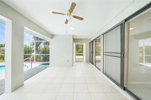 unfurnished sunroom featuring ceiling fan, a pool, and a wealth of natural light