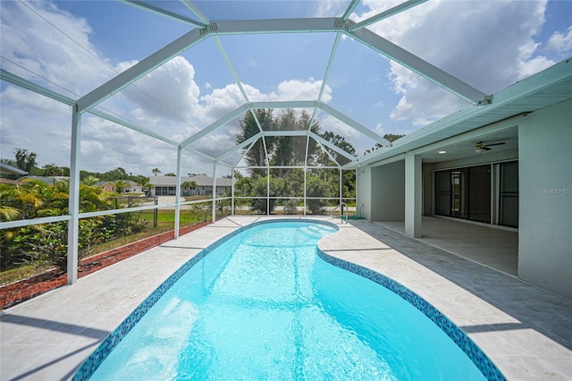 view of pool with ceiling fan, a patio area, and glass enclosure