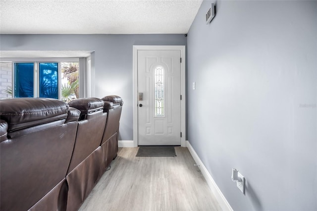 entryway with light wood-type flooring and a textured ceiling