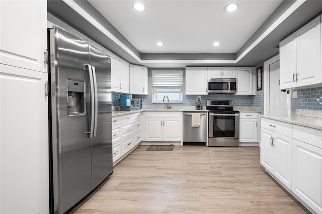 kitchen with white cabinets, light wood-type flooring, stainless steel appliances, and sink