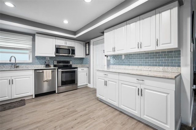 kitchen featuring white cabinetry, sink, stainless steel appliances, and light hardwood / wood-style floors