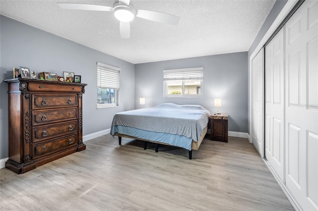 bedroom featuring ceiling fan, a closet, light hardwood / wood-style floors, and a textured ceiling