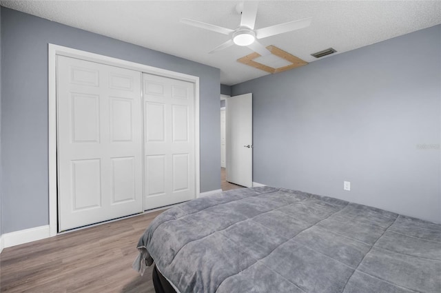 bedroom featuring ceiling fan, a closet, hardwood / wood-style floors, and a textured ceiling