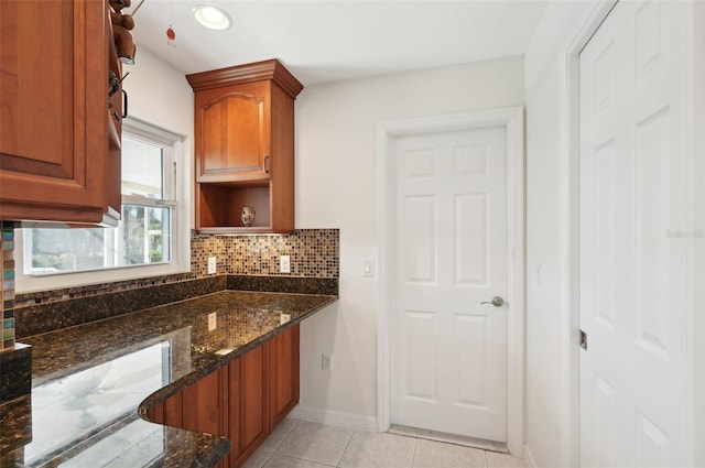 kitchen featuring decorative backsplash, light tile patterned floors, and dark stone countertops