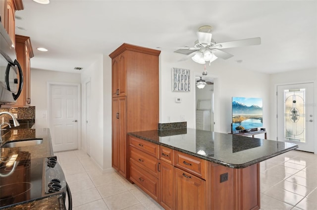 kitchen featuring ceiling fan, sink, light tile patterned floors, and dark stone counters