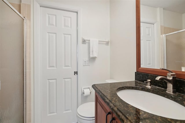 bathroom with vanity, toilet, and a shower with shower door