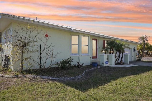 property exterior at dusk featuring a lawn