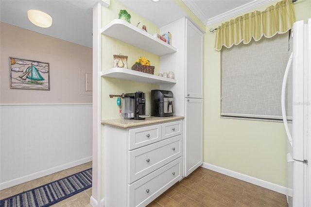 kitchen featuring white cabinetry, crown molding, light hardwood / wood-style floors, and white refrigerator