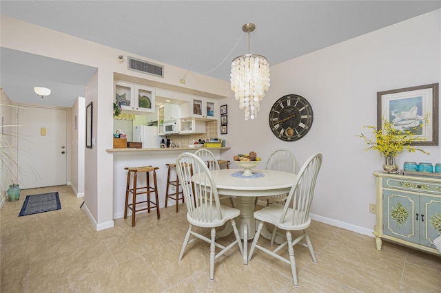 dining area with light tile patterned floors and an inviting chandelier