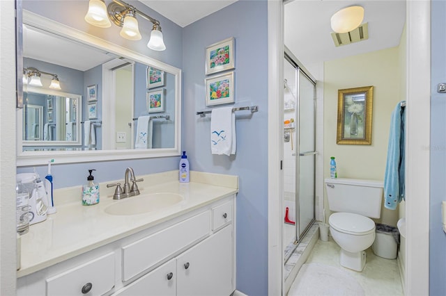 bathroom featuring tile patterned flooring, vanity, toilet, and a shower with door