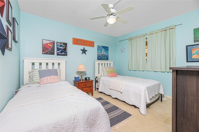 bedroom featuring ceiling fan, light colored carpet, and a textured ceiling