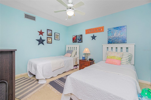 carpeted bedroom with ceiling fan and a textured ceiling