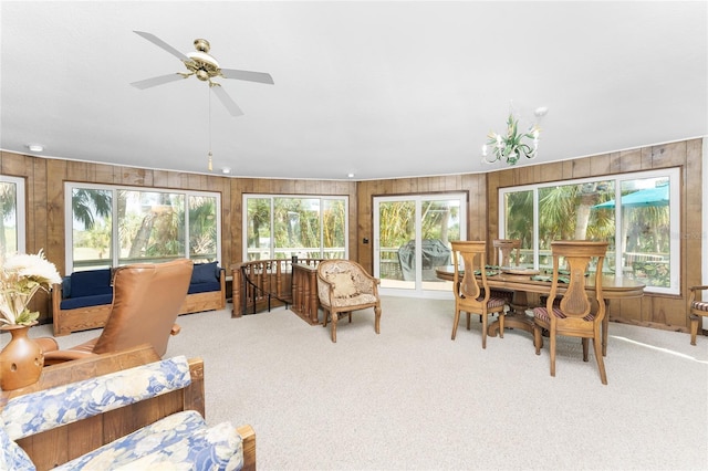 sunroom featuring ceiling fan with notable chandelier