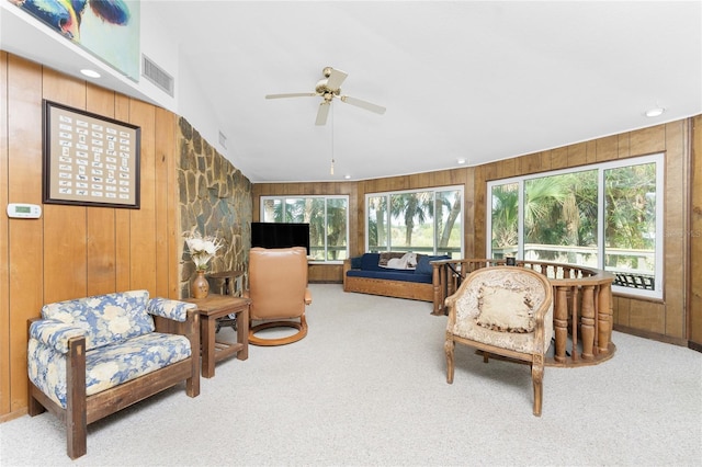 carpeted living room featuring wood walls, ceiling fan, and vaulted ceiling