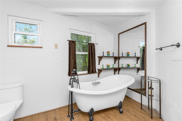 bathroom with hardwood / wood-style floors, toilet, and a bathing tub